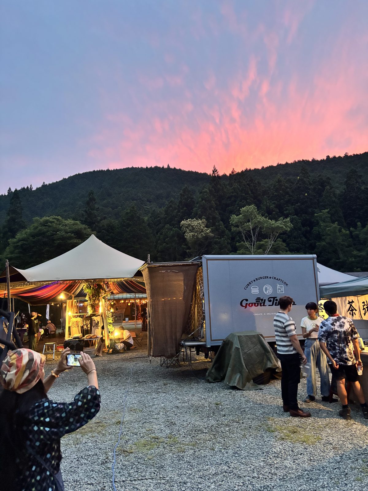 alba al festival Moment, Monte Omine: cielo rosa pastello, stand illuminati, sagoma dei cedri